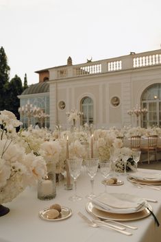 the table is set with white flowers and place settings for an elegant dinner or reception