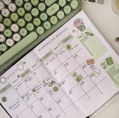 an open planner sitting on top of a desk next to a keyboard