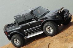 a black toy truck on top of a rock