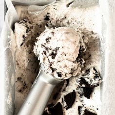 an ice cream scoop full of chocolate chip cookies and oreo cookie chunks in a white container