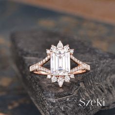 an engagement ring with a large emerald cut diamond surrounded by small diamonds on top of a rock