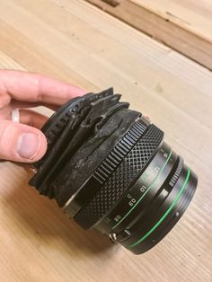 a hand holding a camera lens on top of a wooden table