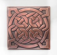 a square tile with an intricate design on the front and back side, in copper