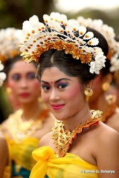 the women are dressed in yellow dresses and headpieces with flowers on their heads