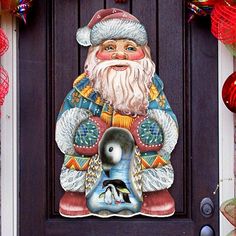 a door with a christmas decoration on it and a santa clause holding a penguin in his hand