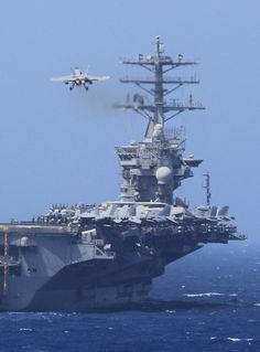 an aircraft is taking off from the flight deck of a ship in the ocean with another plane flying over it