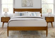 a bed with two night stands next to each other in a white and wood bedroom