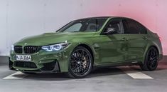 the green bmw m4 is parked in a parking lot with its lights on and it's door open