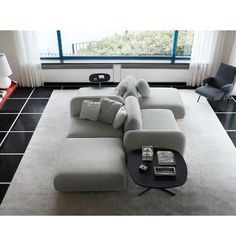 a modern living room with black tile flooring and white furniture, including a sectional sofa