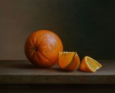 an orange cut in half sitting on top of a wooden table next to another piece of fruit