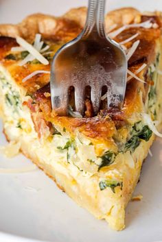 a slice of quiche on a plate with a fork stuck in the crust and cheese