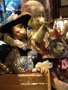 an assortment of figurines are on display in a store window, with one holding a disco ball and the other wearing a hat