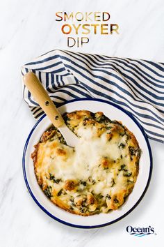 a white plate topped with cheese and spinach covered in sauce next to a blue and white towel