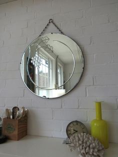 a mirror hanging on the side of a white brick wall next to a yellow vase