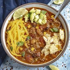 a bowl filled with chili, beans, cheese and tortilla chips on top of a blue towel