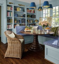 a dining room with blue walls and wooden flooring, built in bookshelves