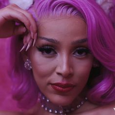 a woman with bright pink hair and pearls on her head is posing for the camera