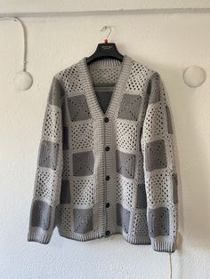 a gray and white sweater hanging on a wall