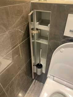 a bathroom with a toilet next to a sink and a shelf in the corner that is open