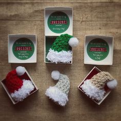 four small knitted santa hats in boxes on a table next to some stickers