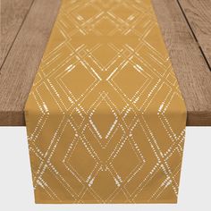 a yellow table runner sitting on top of a wooden table next to a brown bench