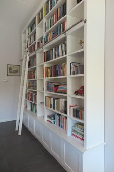 there is a ladder leaning up against the bookshelves in this white bookcase