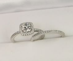 an engagement ring with a cushion cut diamond in the center and pave set diamonds on each band