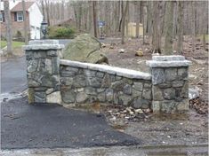 a stone wall and gate in the middle of a driveway