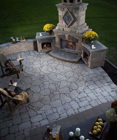 an image of a fire place in the middle of a patio with chairs around it