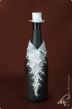 a black bottle with white flowers and a top hat on it's cap is sitting on a brown surface