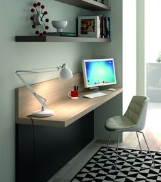 a computer monitor sitting on top of a wooden desk next to a lamp and bookshelf