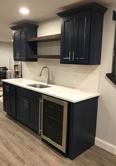 an empty kitchen with dark blue cabinets and white counter tops is seen in this image