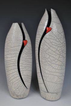 two white vases with black lines and red hearts on the sides, one is shaped like a heart