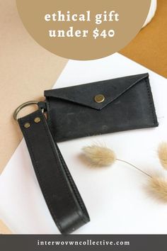 a black leather wallet sitting on top of a table next to a white envelope and some dry grass