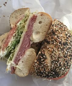 a sandwich cut in half sitting on top of a piece of paper covered in sesame seeds