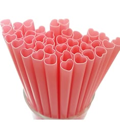 a vase filled with lots of pink heart shaped plastic straws on top of a white table