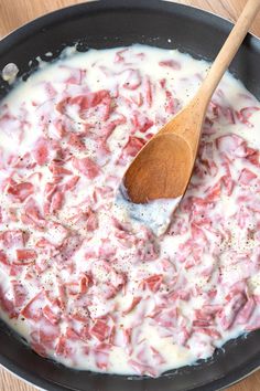 a wooden spoon is in a skillet filled with meat and sauces on the table