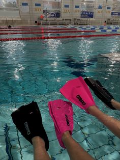 two people are swimming in a pool with their feet up on the water's edge