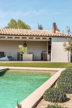 a house with a pool in front of it and an outdoor lounge area on the other side