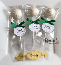 four golf balls with green bows on them in cellophane bags for wedding favors