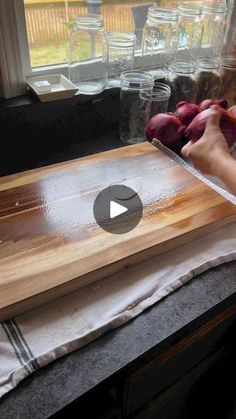 a person cutting up vegetables on top of a wooden cutting board in front of a window