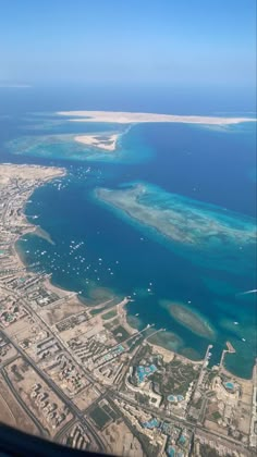 the view from an airplane looking down at some blue water and white sand beach in the distance