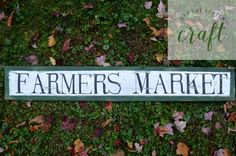 a sign that says farmer's market on it in front of some grass and leaves