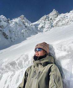 a woman laying down in the snow with her arms behind her back, wearing skis