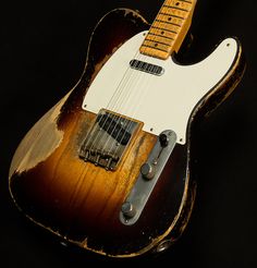 an old, worn out guitar sits on a black background