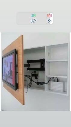 a tv mounted to the side of a white wall next to a shelf with wires