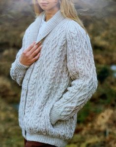 a woman wearing a white sweater and brown pants with her hands in her pockets, posing for the camera