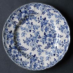 a blue and white plate sitting on top of a black tablecloth with flowers in it