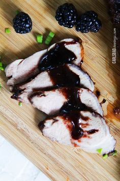 some meat is sitting on a cutting board with blackberries