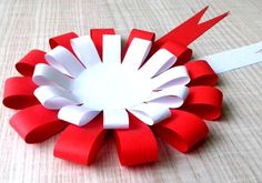 a red and white flower made out of paper on a table with a pair of scissors next to it